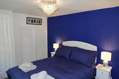 a blue bedroom with a bed and a chandelier at Saffron House in Fowey