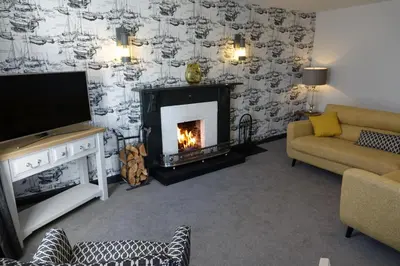 a living room with a fireplace and a tv at Saffron House in Fowey