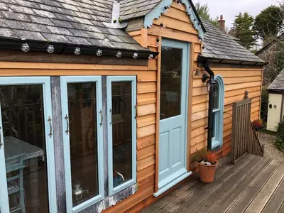 a cabin with sliding glass doors on a deck at Enys Boathouse in Porkellis