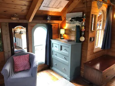 a room with a dresser and a chair in a tiny house at Enys Boathouse in Porkellis