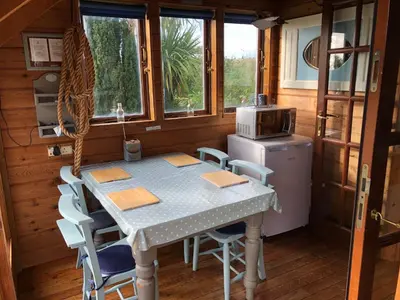 a kitchen with a table and chairs and a refrigerator at Enys Boathouse in Porkellis