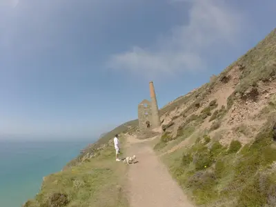 a person and two dogs on a path to a lighthouse at Rosenn Teyr in St. Agnes