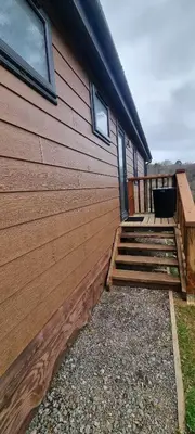 a house with a wooden deck next to a building at Peacock Lodge - Sleeps 4 - 2 Bedrooms in East Looe