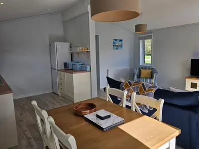 a kitchen and living room with a table and a blue couch at Peacock Lodge - Sleeps 4 - 2 Bedrooms in East Looe