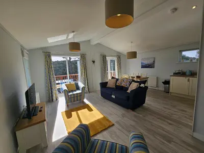 a living room with a couch and a table at Peacock Lodge - Sleeps 4 - 2 Bedrooms in East Looe
