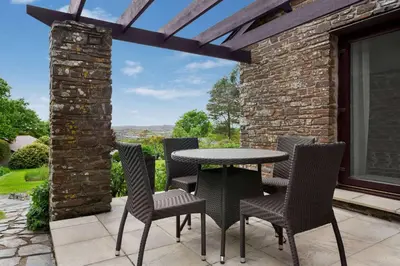 a table and chairs on a patio with a view at Trenython Manor Resort in Fowey