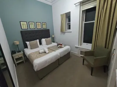a bedroom with a large bed and a chair at Trenython Manor Resort in Fowey