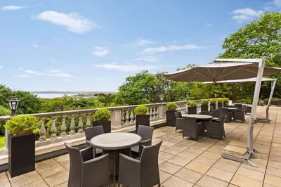 a patio with tables and chairs and an umbrella at Trenython Manor Resort in Fowey
