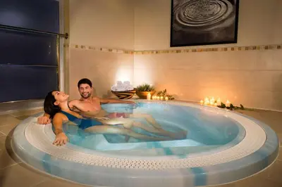 a man and a woman laying in a hot tub at Trenython Manor Resort in Fowey