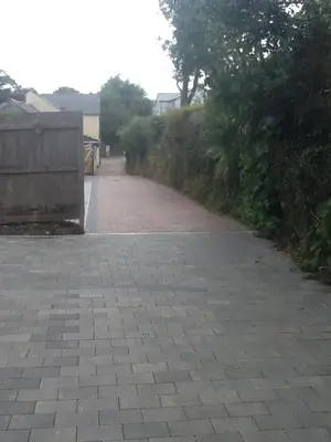 a brick road with a fence and trees on it at Boleyn house in Bodmin