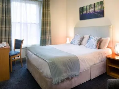 a bedroom with a large bed and a chair at The White Hart Hotel in St Austell