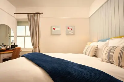 a bedroom with a bed and a desk and a window at Rashleigh Arms in St Austell