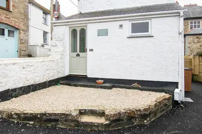 a white garage with a door and some gravel at Rosevean Cottage St Agnes in St. Agnes