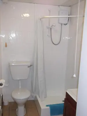 a white bathroom with a toilet and a shower at Wheal Rodney Holiday Park in Marazion