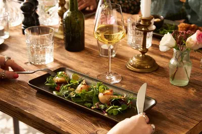 a table with a plate of food and a glass of wine at Pedn-Olva in St Ives
