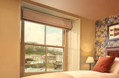 a bedroom with a large window with a view at Harbour Inn in Porthleven