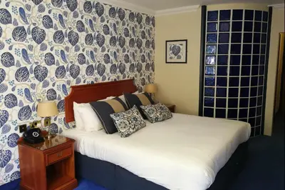 a bedroom with a bed with a blue and white patterned wall at Penventon Park Hotel in Redruth
