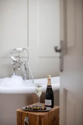 a bottle of wine and a glass on a wooden table in a bathroom at Penventon Park Hotel in Redruth