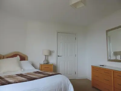 a bedroom with a bed and a dresser and a window at Sea Breeze Apartment in St Austell