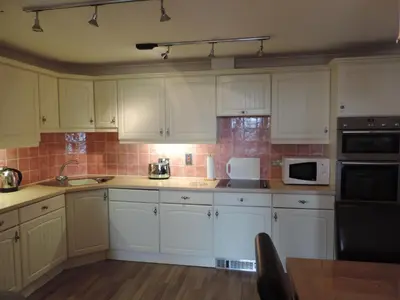 a kitchen with white cabinets and a sink and a microwave at Sea Breeze Apartment in St Austell