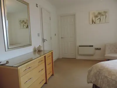a bedroom with a dresser and a mirror at Sea Breeze Apartment in St Austell