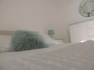 a white bed with a furry pillow on top of it at Sea Breeze Apartment in St Austell