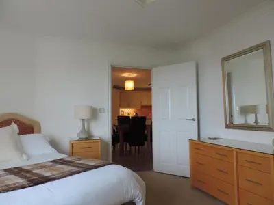 a bedroom with a bed and a dining room at Sea Breeze Apartment in St Austell