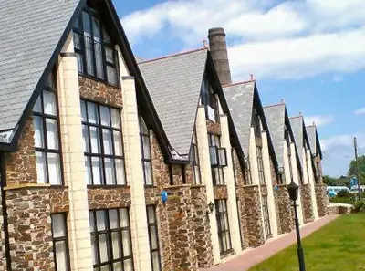 a large brick building with windows and a roof at Sea Breeze Apartment in St Austell