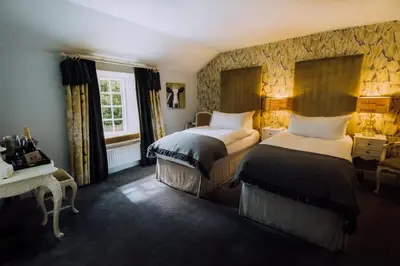 a bedroom with two beds and a desk and a window at Boscundle Manor in St Austell