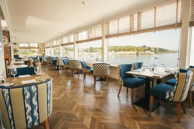 a restaurant with tables and chairs and a view of the water at Greenbank Hotel in Falmouth