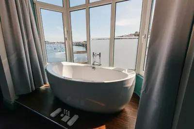 a bath tub in a room with a large window at Greenbank Hotel in Falmouth