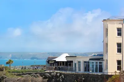a building on a hill with the ocean in the background at Great Western in Newquay