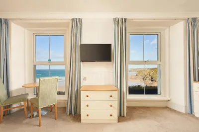 a room with two windows and a desk and a table at Great Western in Newquay