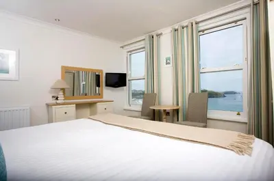 a bedroom with a large bed and two windows at Great Western in Newquay
