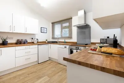 a kitchen with white cabinets and a wooden counter top at Oasis House in Falmouth