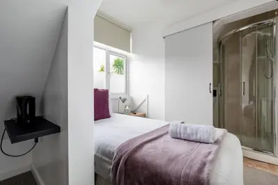 a white bedroom with a bed and a window at Oasis House in Falmouth
