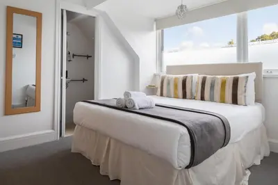 a white bedroom with a large bed with a window at Oasis House in Falmouth