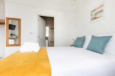 a bedroom with a large white bed with blue pillows at Oasis House in Falmouth