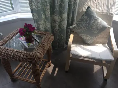 a wicker chair and a table with a vase of flowers at The garden apartment in St Ives