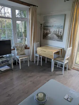 a living room with a wooden table and chairs at The garden apartment in St Ives