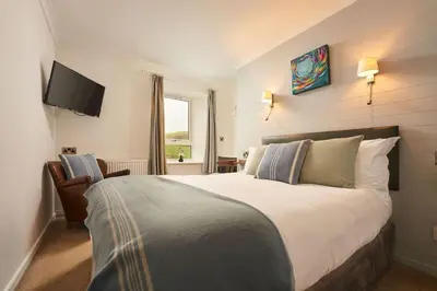 a bedroom with a large bed and a flat screen tv at Port William Inn in Tintagel