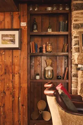 a room with a chair and a shelf of books at Port William Inn in Tintagel