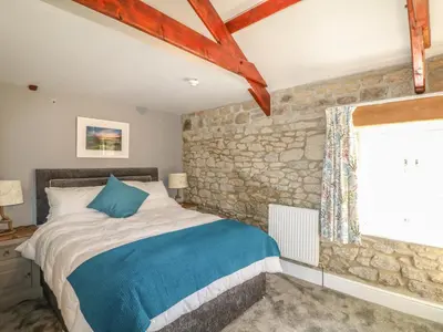 a bedroom with a bed and a stone wall at Helford in Penryn