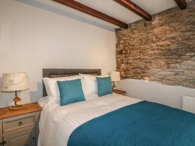 a bedroom with a bed and a stone wall at Helford in Penryn