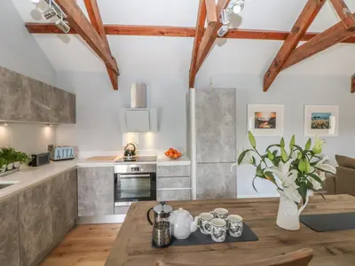 a kitchen with a wooden table in a room at Helford in Penryn