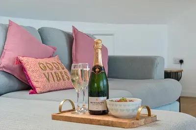 a bottle of champagne and a glass on a tray on a couch at Sunset View in Newquay