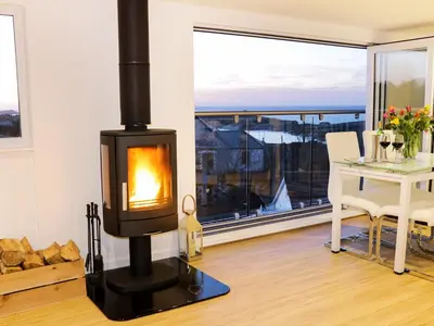 a wood stove in a living room with a table at Sunset View in Newquay