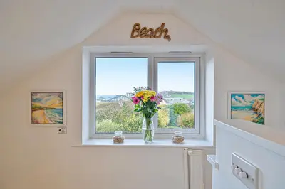 a vase of flowers sitting on a window in a room at Sunset View in Newquay