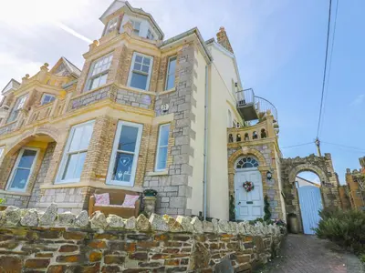 an old stone house with a stone wall at Spiral View in Perranporth