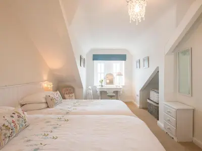 a white bedroom with a bed and a desk at Spiral View in Perranporth
